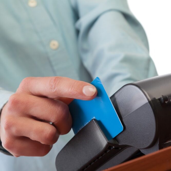 Human hand with credit card swipe through terminal for sale, isolated on white background.