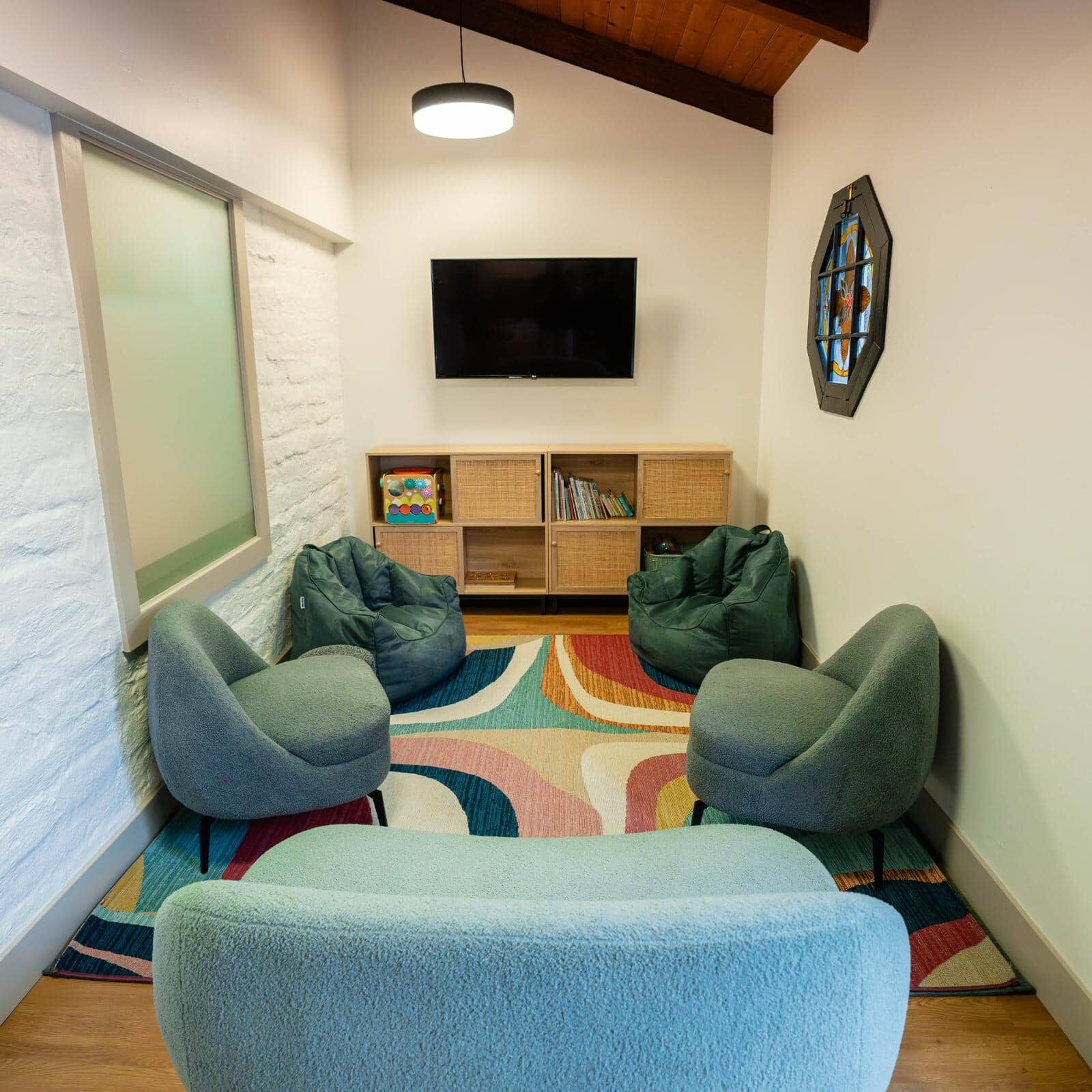 Cozy waiting area at North County Orthodontics featuring comfortable seating, a television, and colorful decor, designed for families visiting for braces and clear aligner consultations.